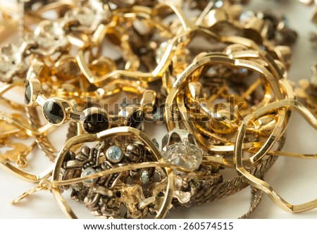 Closeup picture of heap of golden and silver decorations and jewels combined with different inexpensive rocks symbolizing treasure, rich and wealth concept