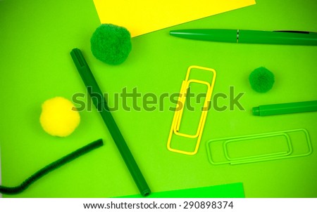Arrangement of playful vivid office items as yellow and green paperclips, writing tools and yellow card, soft fuzzy fluffy balls, symbolizing playful concept on everyday desk work activities