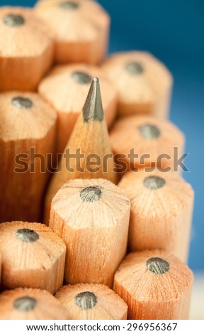Macro image of graphite tip of a sharp ordinary wooden pencil as drawing and drafting tool, standing among other pencils, symbolizing individuality approach and concept as standing out from the crowd