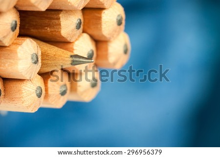 Macro image of graphite tip of a sharp ordinary wooden pencil as drawing and drafting tool, standing among other pencils, symbolizing individuality approach and concept as standing out from the crowd