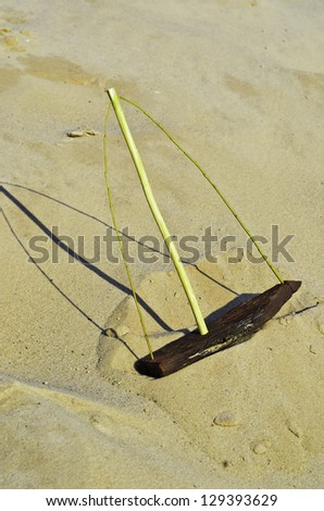 Wooden toy ship with a mast on sandy waves on a background a serene.