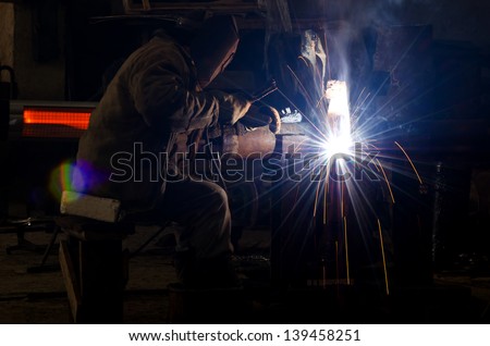 Sparks and drops of molten metal during work of welder.