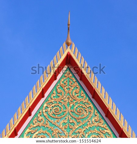 Gable apex on Thai temple roof in blue sky.