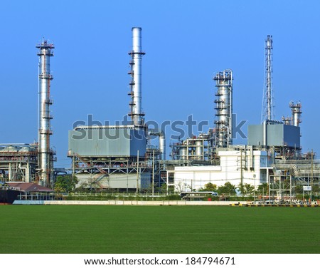 Oil and gas refinery with reflection on green field - Petrochemical factory