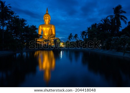 Big Buddha statue with reflection on water in the evening.