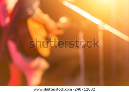 blurred woman guitar player on concert stage