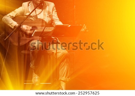 man playing music by wooden acoustic guitar in the concert stage