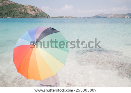Hipster color. girl with color full umbrella on the sandy beach