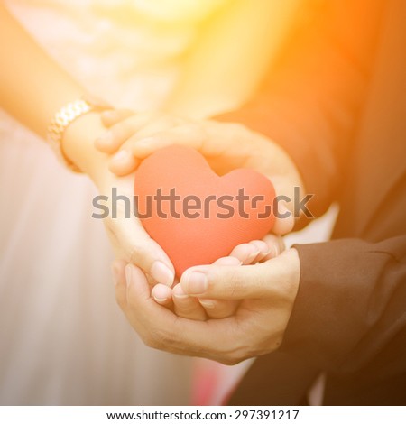 Bride and groom with a red heart in hands