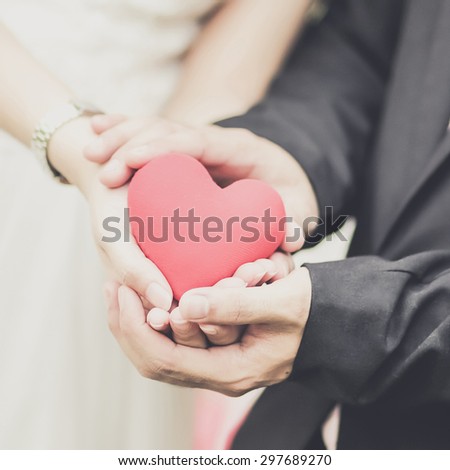 Bride and groom with a red heart in hands