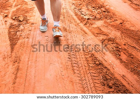 legs of sport man walking on the mud path