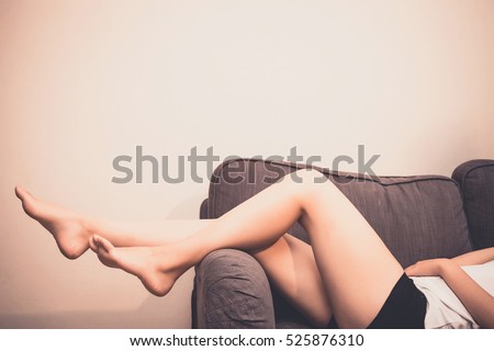 Long woman legs on sofa.