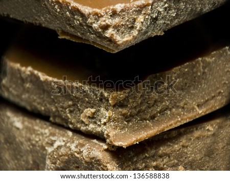 Extreme closeup of sweet, milk chocolate pieces stack background or texture