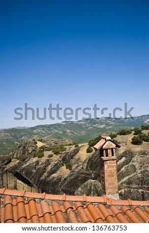 Roof with chimney against mountain landscape in Greece