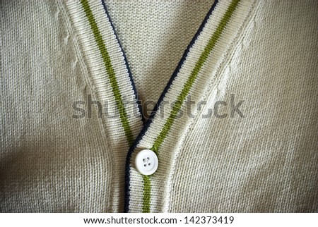 White or beige cardigan sweater with green and blue stripes closeup