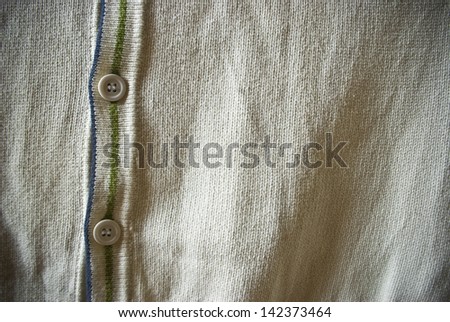 White or beige cardigan sweater with green and blue stripes closeup