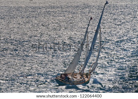 A regatta wooden ship with solitary captain sailing in the blue sea