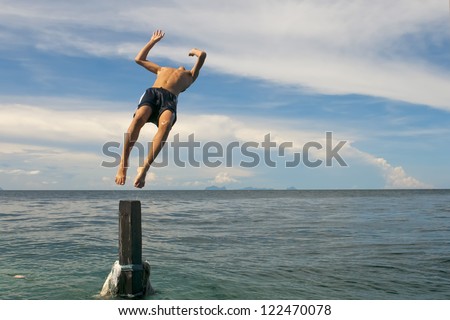 A young man jumping into the Turquoise Tropical Polynesian Paradise Beach Ocean Sea Crystal Water Clear sea star down under