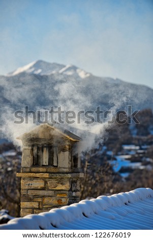 A mountain house roof with smoking chimney