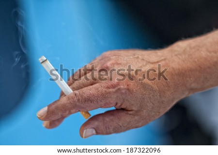 old man hand wgile holding a smoking cicgarette