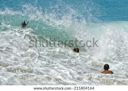 children playing in sea waves in hawaian sandy beach