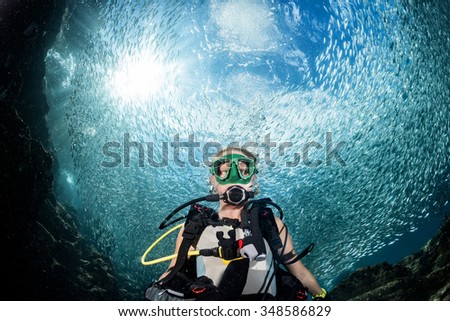 beautiful diver blonde girl diving in the deep blue sea  Inside a school of fish