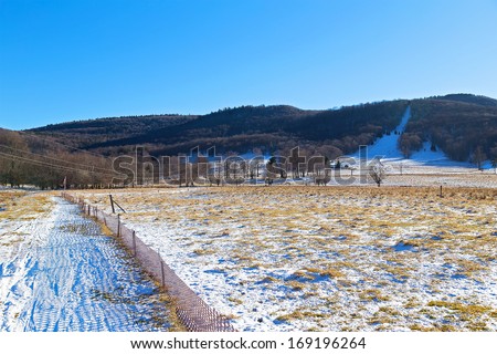 Skiing fields in West Virginia with picturesque background of trees and forestry hills. Snow is melting on the skiing fields surrounded by a tranquil countryside landscape.