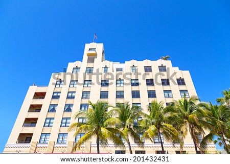 Frontage of art deco building of Miami Beach, Florida. Palms and building against a clear blue sky.