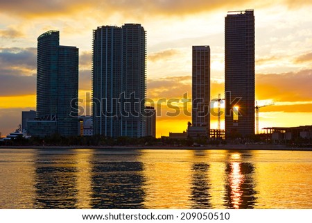 Skyscrapers near the waterfront with bright sunset at the background. Sunset over Miami city, Florida.