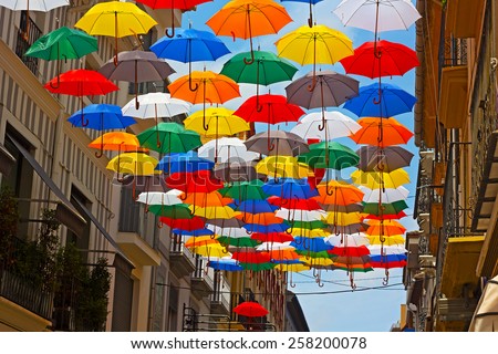 Colorful umbrellas installed on the street in Spanish city. Urban sun protection with umbrellas at work.