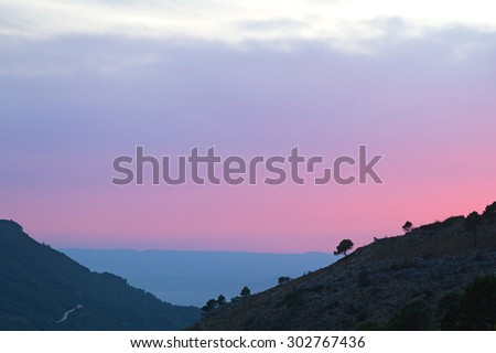 Scenic sunset in the mountains. The pink and grey colors of sunset in the mountain valley in rural Spain near Valencia.