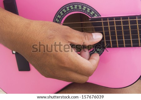 Young man close up shot of strings and guitarist hands playing guitar over black - shallow DOF with focus on hands