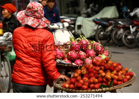 Hanoi, Vietnam - February 6, 2013: A woman is carrying his loaded bicycle with fruits through the crowds of the city of Hanoi, Vietnam.