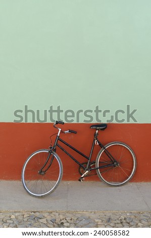 Old black bicycle leaning against a house wall with copy space.