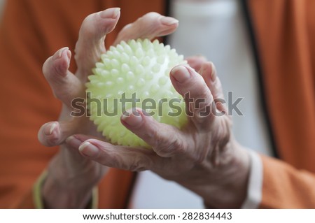 Application in physiotherapy, Senior massaging her hands with a spiky ball