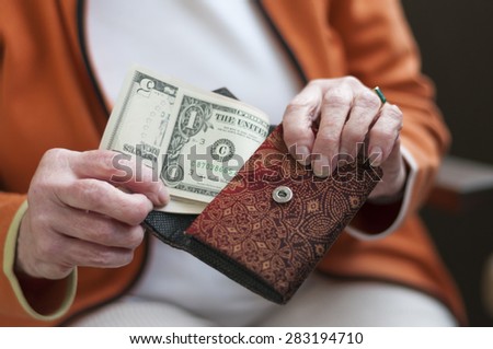 Senior women looks in her purse with US dollar bills.