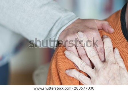 Young woman holds a hand on the shoulder of a senior citizen.