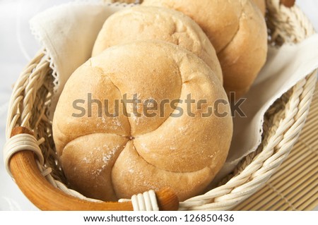 Basket full of white wheat bread rolls, freshly baked and ready for breakfast.