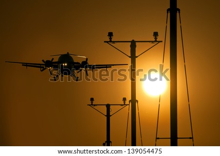Passenger turbo propeller aircraft approaching the runway at sunset