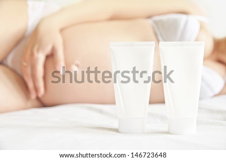 Cosmetics for pregnant women - two cream tubes with a pregnant woman lying in the background