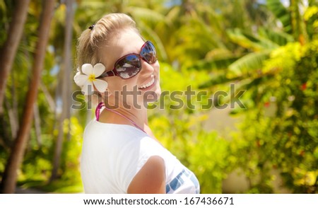 Natural shot of a beautiful girl smiling to the camera in a tropical outdoor