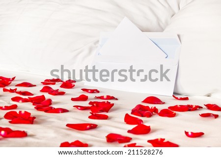 Romantic letter - an envelope lying on a bed among rose petals and pillows