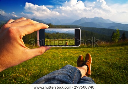 Man taking a photo of a mountain landscape with his phone - point of view shot