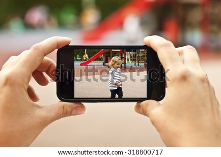 Woman taking a photo of baby girl with smartphone - POV shot