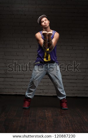 hip-hop style man holding chain over dark brick wall on background