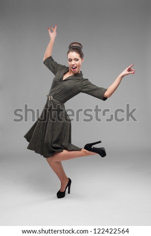 cheerful young caucasian woman in green vintage dress dancing isolated on gray