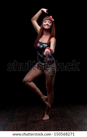 young caucasian red-haired female dancer showing move over black background
