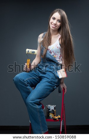 happy smiling painter woman standing at ladder and holding roll