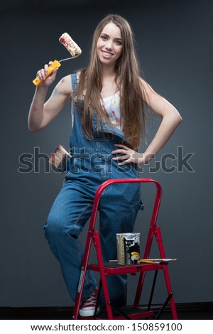 happy smiling painter woman standing at ladder and holding roll