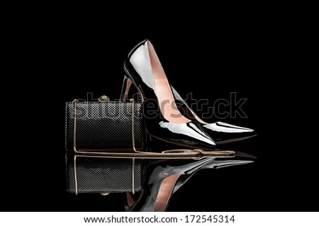 composition of black female high heel shoes and clutch isolated on black